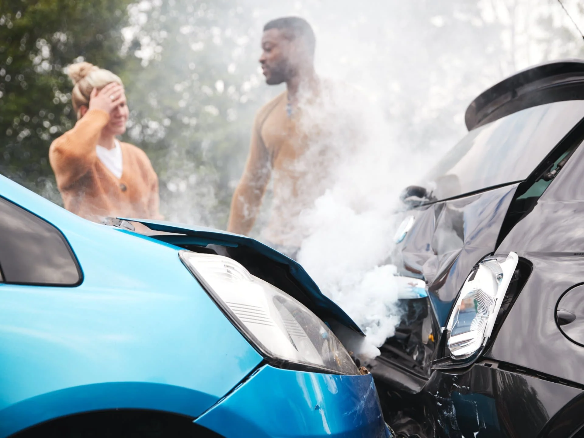Two damaged cars with smoke rising between them.