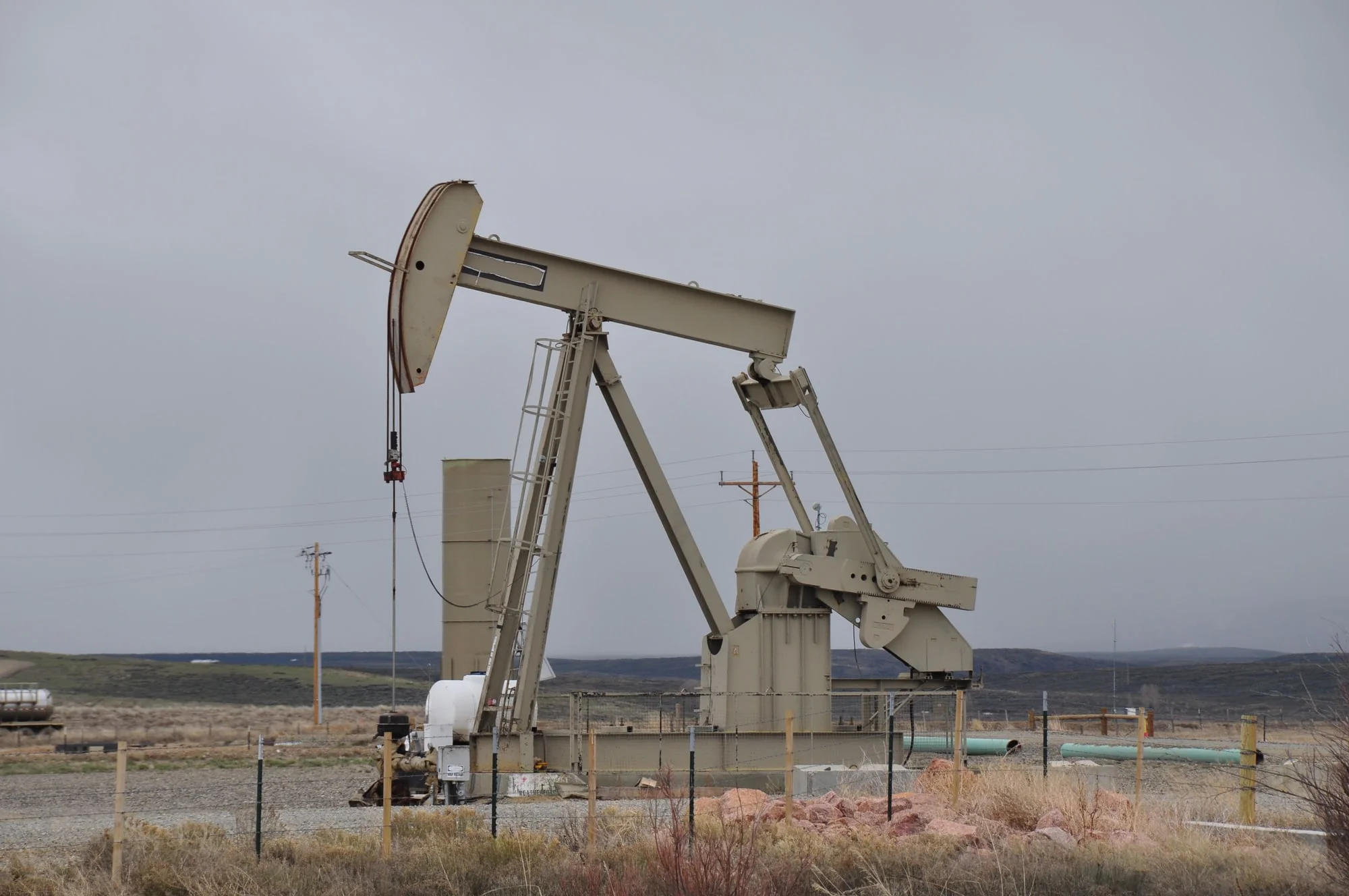 An onshore pumpjack beneath an overcast sky.